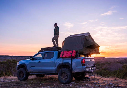 Man on top with installed Tent and Cali Raised Overland Bed Rack | 2005-2023 Toyota Tacoma